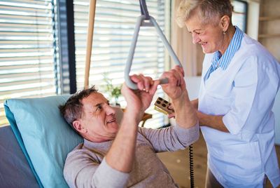 Elderly man being assisted upright in bed by home health professional