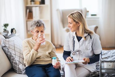 Orthopedic technician helping man in wheelchair put cast on his leg