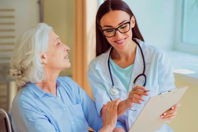 Nurse caring for and presenting care plan to elderly woman at home