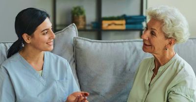 Home health care professional consulting with smiling woman in her home