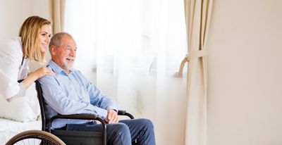 Home health physician and man in wheelchair at home staring hopefully into the distance